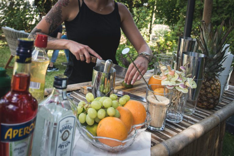Frau schneidet Zitrusfrüchte für Cocktails auf der Terrasse.