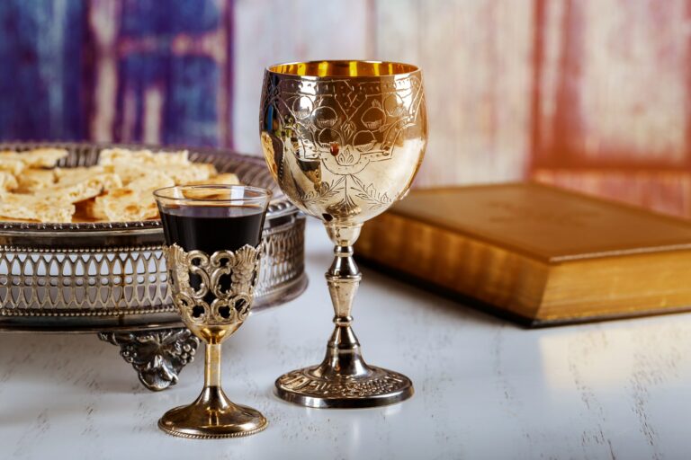 Elegante, silberne Weingläser mit Rotwein, auf weißem Tisch.